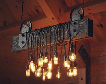 May include: A rustic wooden beam with black metal hardware and a pulley system holds a chandelier with multiple Edison bulb lights.