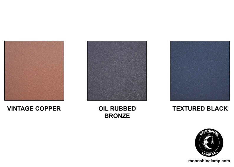 Puede incluir: Tres muestras de color que muestran diferentes acabados para una l&aacute;mpara de metal. Las muestras est&aacute;n etiquetadas como "Cobre Vintage", "Bronce Frotado con Aceite" y "Negro Texturizado".