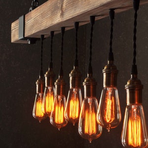 Op de afbeelding: Een rustieke houten balk-kroonluchter met 10 blootliggende gloeilampen. De lampen hangen aan zwarte snoeren en hebben een warme, amberkleurige gloed.