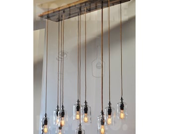 May include: A rustic wooden chandelier with 10 clear glass pendant lights hanging from rope cords. The lights are turned on and illuminate the room.
