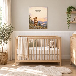 Woodland bear canvas in a nursery on a greige wall above a wooden crib and white wainscoting, showing sample name Eleanor Mae and birth details.