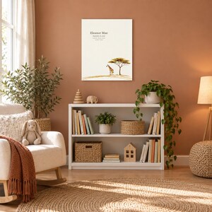 Safari giraffe canvas in a nursery on a terracotta wall above a white bookshelf, showing sample name Eleanor Mae and birth details.