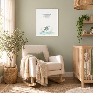 Sea turtle canvas in a nursery on a sage green wall above a cream rocking chair, showing sample name Eleanor Mae and birth details.
