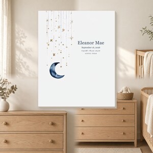May include: A white rectangular wall art print featuring a dark blue watercolor crescent moon and gold hanging stars and bows. The text reads Eleanor Mae, September 16, 2026, 6:42 AM, 7 lb 4 oz, 20.5 in, and AUSTIN, TEXAS in dark blue lettering.