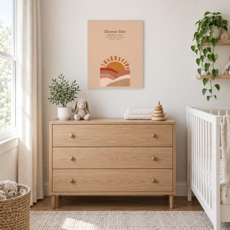 Boho sun canvas in a nursery above a light oak dresser beside a white crib, showing sample name Eleanor Mae and birth details.
