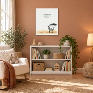 Baby zebra canvas in a nursery on a terracotta wall above a white bookshelf, showing sample name Eleanor Mae and birth details.