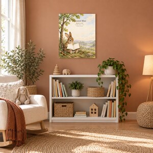 Storybook rabbit canvas in a nursery on a terracotta wall above a white bookshelf, showing sample name Eleanor Mae and birth details.