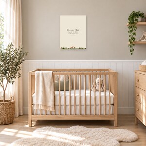 Woodland birth stats sign in a nursery on a greige wall above a wooden crib and white wainscoting, showing sample name Eleanor Mae and birth details.