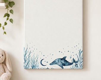 May include: A rectangular canvas wall art piece featuring a watercolor illustration of a dark blue whale swimming among light blue seaweed and bubbles. A small crescent moon is positioned near the whale on a clean, white background.