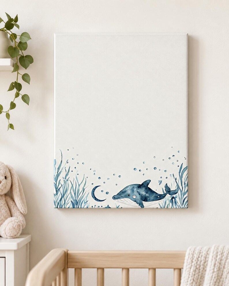 Wrapped ocean nursery canvas with a blue watercolor whale, crescent moon, bubbles and sea plants displayed above a crib.