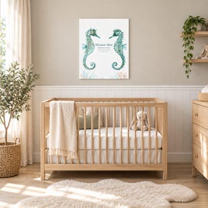 Seahorse reef canvas in a nursery on a greige wall above a wooden crib and white wainscoting, showing sample name Eleanor Mae and birth details.