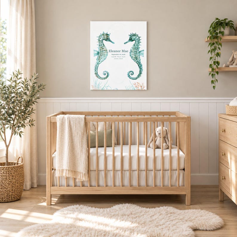 Seahorse reef canvas in a nursery on a greige wall above a wooden crib and white wainscoting, showing sample name Eleanor Mae and birth details.