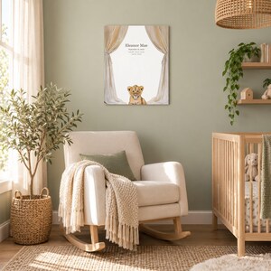 Lion cub canvas in a nursery on a sage green wall above a cream rocking chair, showing sample name Eleanor Mae and birth details.