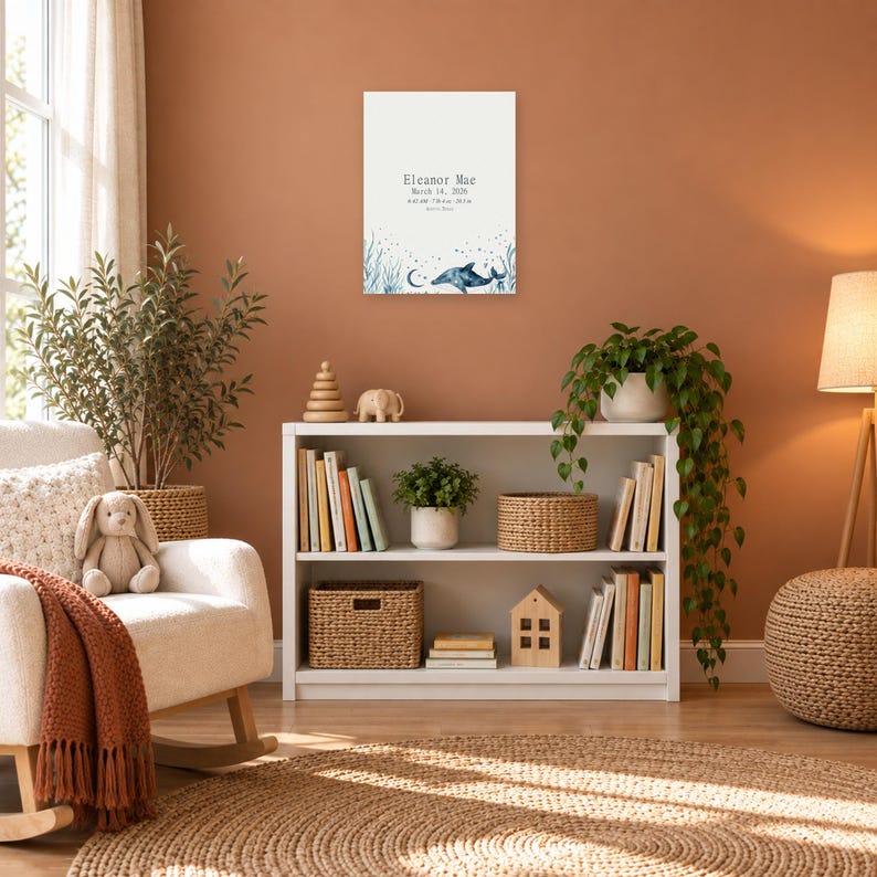 Ocean birth stats sign in a nursery on a terracotta wall above a white bookshelf, showing sample name Eleanor Mae and birth details.