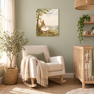Storybook rabbit canvas in a nursery on a sage green wall above a cream rocking chair, showing sample name Eleanor Mae and birth details.