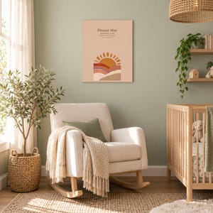 Boho sun canvas in a nursery on a sage green wall above a cream rocking chair, showing sample name Eleanor Mae and birth details.