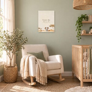 Safari birth stats sign in a nursery on a sage green wall above a cream rocking chair, showing sample name Eleanor Mae and birth details.
