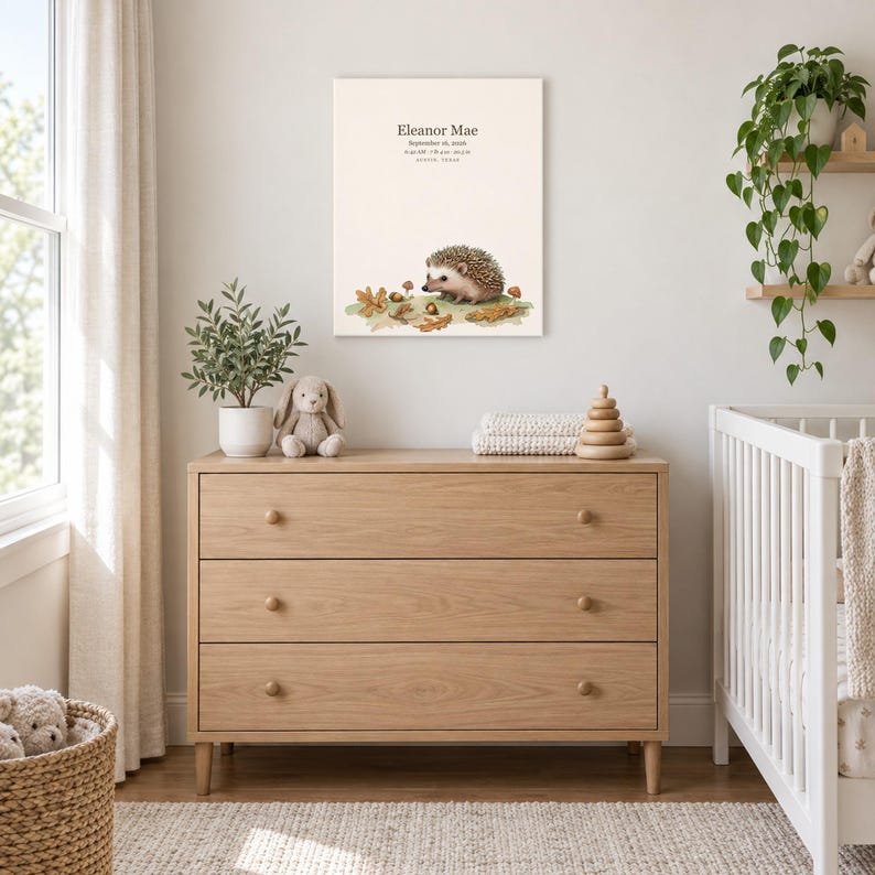 Storybook hedgehog canvas in a nursery above a light oak dresser beside a white crib, showing sample name Eleanor Mae and birth details.
