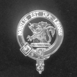 May include: A silver-colored clan crest with a lion rampant and the text "Nobilis Est Ira Leonis" around the outer edge.