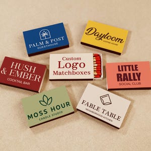 May include: Six rectangular matchboxes with various brand logos and names including Palm & Post, Dayloom, Hush & Ember, Custom Logo Matchboxes, Little Rally, Moss Hour, and Fable Table. The boxes feature different colors and typography styles.