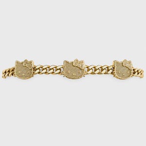 May include: A gold-toned chain bracelet featuring three evenly spaced, textured Hello Kitty character charms. The bracelet is constructed with interlocking curb links, and each charm displays the iconic cat face with a bow on the side.