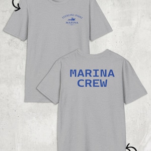 May include: A light grey short-sleeved t-shirt featuring a blue graphic on the front chest that reads Sterling Point Marina with a boat icon. The back of the shirt displays the text Marina Crew in large blue capital letters. The shirt is shown from both front and back views.