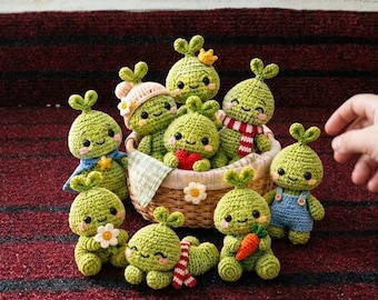 May include: A collection of small, green, round crocheted figures with sprout-like tops, black eyes, and pink cheeks. Some figures wear accessories like a blue cape, a pink hat, a red scarf, or blue overalls, while others hold a red heart, a white flower, or an orange carrot.