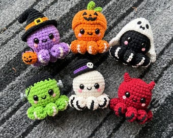 May include: Six small crocheted octopus plushies featuring Halloween themes. One is purple with a witch hat, one is orange as a pumpkin, one is black as a ghost, one is green as a monster, one is white with a skull hat, and one is red as a devil.