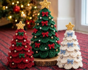 May include: Three cone-shaped crochet Christmas trees in red, green, and white. Each tree features a yellow star topper, small bows, and spherical ornaments. The red tree has green bows, the green tree has red bows, and the white tree has blue bows.