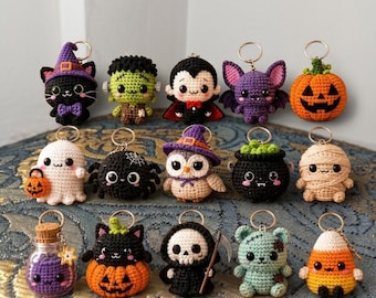 May include: A collection of fifteen small, crocheted Halloween-themed keychains featuring various characters including a black cat, Frankenstein's monster, a vampire, a bat, a pumpkin, a ghost, a spider, an owl, a cauldron, a mummy, a potion bottle, a cat in a pumpkin, a grim reaper, a zombie, and candy corn.