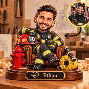 Puede incluir: Una figura bobblehead personalizada de un bombero con barba, vistiendo un uniforme negro con franjas reflectantes amarillas, sentado en un sillón de cuero marrón. Incluye una boca de incendio roja, una manguera amarilla, un casco FD rojo y una base con el nombre Ethan.