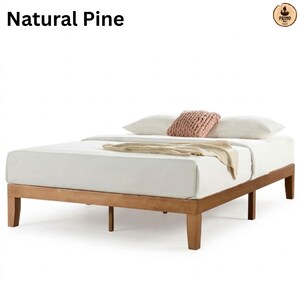 May include: A natural pine wood bed frame with a low-profile design, featuring straight legs and a rectangular base. The bed is dressed with a white mattress, two white pillows, a textured peach-colored throw pillow, and a beige knit blanket.