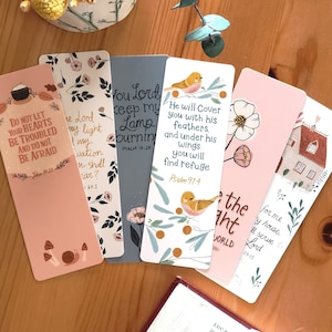 May include: Five colourful bookmarks with floral and bird illustrations and inspirational quotes. The bookmarks feature a variety of colours, including pink, blue, and green. The quotes include "Do not let your hearts be troubled and do not be afraid", "You Lord keep my lamp burning", "He will cover you with his feathers and under his wings you will find refuge", "Be the light", and "For me, my house will serve the Lord".