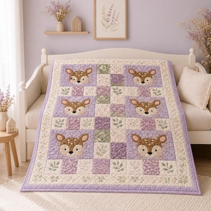 Puede incluir: Una manta acolchada con un patrón repetitivo de seis caras de ciervo marrón sobre un fondo morado claro, intercaladas con cuadrados de estampados florales y de hojas en tonos lavanda, verde y crema, con un borde floral ancho.