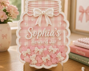 May include: A jar-shaped reward board featuring a pink and white gingham pattern, a white bow at the top, and the text Sophia's Reward Jar. The board is filled with small pink heart-shaped tokens and several white bows, supported by a wooden stand.