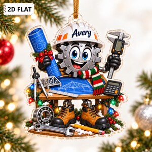 May include: A flat, decorative ornament featuring a cartoon gear character wearing a white hard hat with the name Avery, holding a blue blueprint and a digital caliper. The character sits at a desk with a calculator, compass, and pencil.