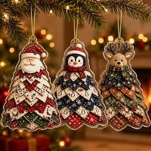 Pode incluir: Três enfeites de árvore de Natal suspensos com um Pai Natal, um pinguim e uma rena. Cada figura tem uma cabeça e um corpo feito de triângulos de tecido acolchoado em camadas com padrões em vermelho, verde, azul e castanho.