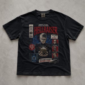 May include: A black short-sleeve t-shirt featuring a Hellraiser graphic print. The design includes the text Hellraiser, Demons to some, angels to others, and Pain is their pleasure, suffering is yours, alongside images of Pinhead and the puzzle box.