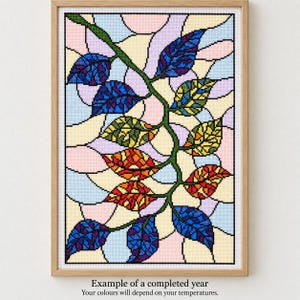 Può includere: Un motivo a punto croce in una cornice di legno raffigurante una vite centrale con foglie multicolori nelle tonalità del blu, verde, giallo e arancione. Lo sfondo è composto da forme curve in stile vetrata nei colori pastello rosa, blu e crema.