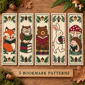 May include: Five rectangular cross-stitch bookmarks featuring woodland animals reading books, including a fox, an owl, a bear, a rabbit, and a hedgehog with a mushroom. Each design is bordered by pine needles and acorns on a cream fabric background.