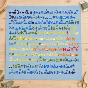 Könnte beinhalten: Ein hellblauer Kreuzstichstoff mit Reihen kleiner, bunter gestickter Symbole wie Häuser, Bäume, Fahrzeuge, Tiere, Sonnen und Sterne. Das Design ist in horizontalen Linien angeordnet und zeigt eine Vielzahl von Formen in blauen, grünen, gelben, orangen und roten Garnen.