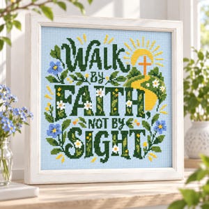 Op de afbeelding: Een ingelijst kruissteek borduurwerk met de tekst WALK BY FAITH NOT BY SIGHT in donkergroene letters. Het ontwerp bevat een gele zon, een kruis, groene heuvels en kleine blauwe en witte bloemen op een lichtblauwe achtergrond met raster.