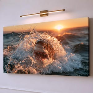 May include: A rectangular wall art canvas depicting a great white shark breaching the ocean surface with its mouth open, surrounded by splashing water. The scene is illuminated by a warm, golden sunset on the horizon, creating high contrast.