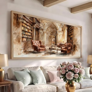 May include: A rectangular wall art print featuring a watercolour-style illustration of a library interior. The scene depicts two brown leather tufted armchairs, a small round table, and tall wooden bookshelves filled with books in a warm, sepia-toned room.