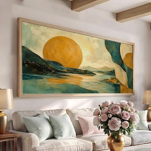 May include: A large rectangular landscape painting in a light wood frame featuring a prominent golden yellow sun setting over a body of water. The scene includes dark teal mountains, rolling hills, and abstract flowing shapes in shades of blue and gold.