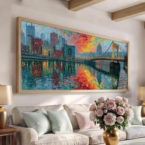 May include: A rectangular wall art print featuring an impressionistic cityscape painting with a bridge spanning a river. The scene displays vibrant orange, yellow, and teal brushstrokes reflecting on the water, framed in a light wood border.