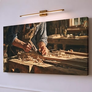 Könnte beinhalten: Ein rechteckiger Wandkunstdruck, der einen Holzwerker in einer braunen Schürze zeigt, der einen Metall-Handhobel auf einem Holzbrett benutzt. Die Szene zeigt Holzspäne auf einer Werkbank, beleuchtet durch eine Leuchte über dem Bild.