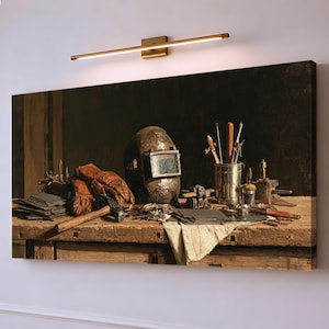 May include: A rectangular canvas print depicting a dark, rustic workshop scene on a wooden workbench. The image features a weathered welding helmet, brown leather gloves, a hammer, metal sheets, and various tools in a metallic container.