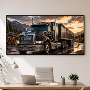 May include: A framed wall art print featuring a black Mack semi-truck with a dump trailer parked on a wet surface. The scene includes a stack of logs, mountains in the background, and a sunset sky with orange clouds. The truck has chrome accents.