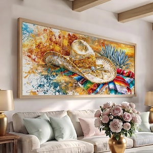 May include: A rectangular wall art print featuring a light-coloured cowboy hat with intricate gold detailing, resting on a vibrant, multi-coloured striped textile next to a spiky agave plant, set against a background of abstract yellow and blue paint splatters.